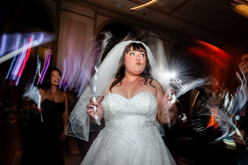 A bride in a white dress dances under dramatic lighting at a wedding reception.