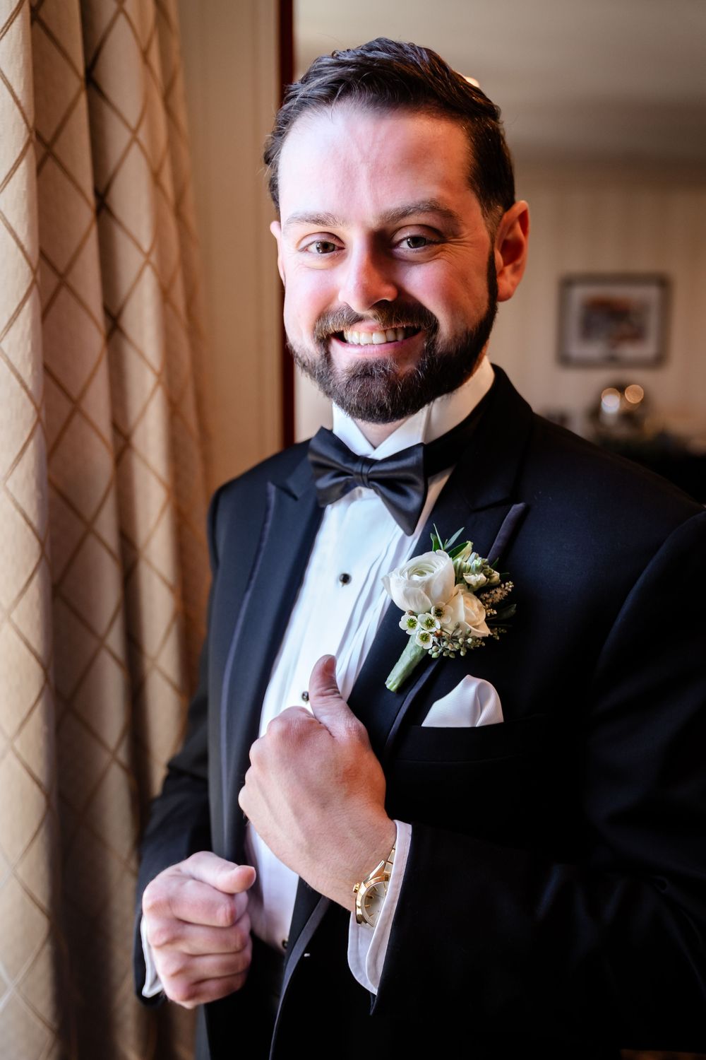 Formal black tuxedo with bowtie and boutonniere detail shots.