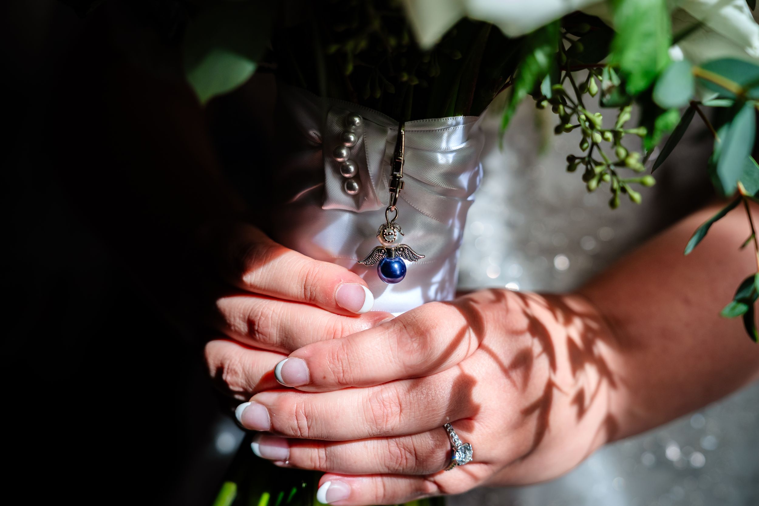 Close-up details of wedding rings and hands in natural light.