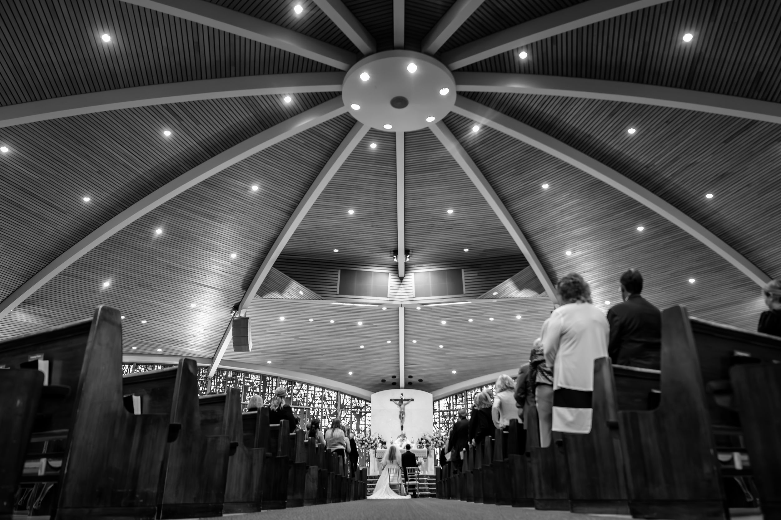 Wedding ceremony under dramatic domed ceiling with modern lighting.