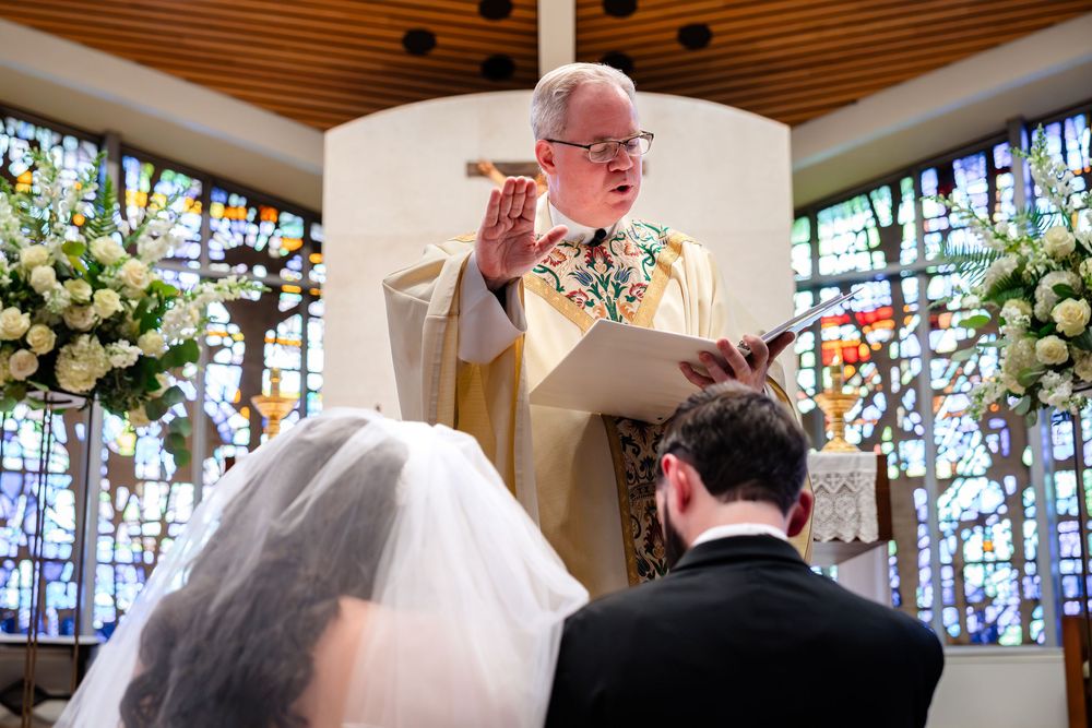 Traditional church wedding ceremony with wooden ceiling beams and colorful stained glass windows.