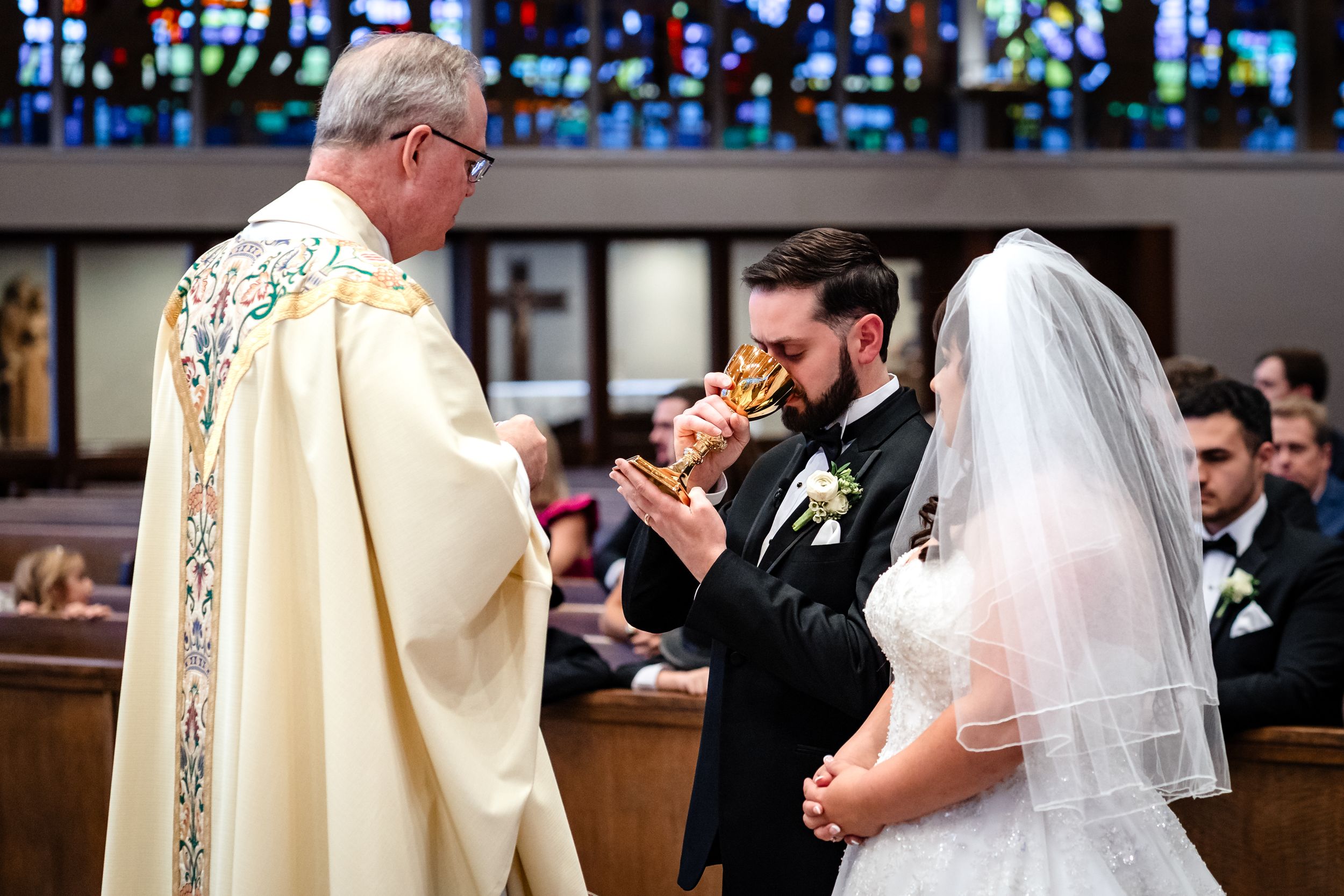 Traditional Catholic wedding ceremony in church with stained glass windows.