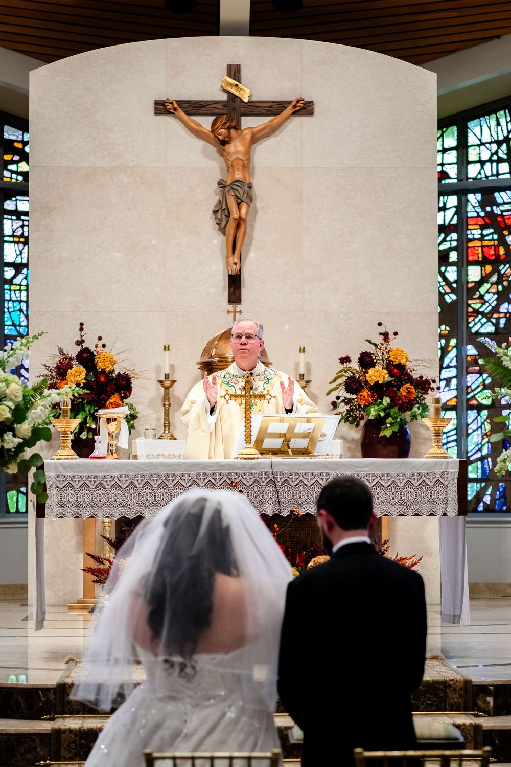 Catholic church altar decorated with flowers and crucifix for a traditional wedding ceremony.