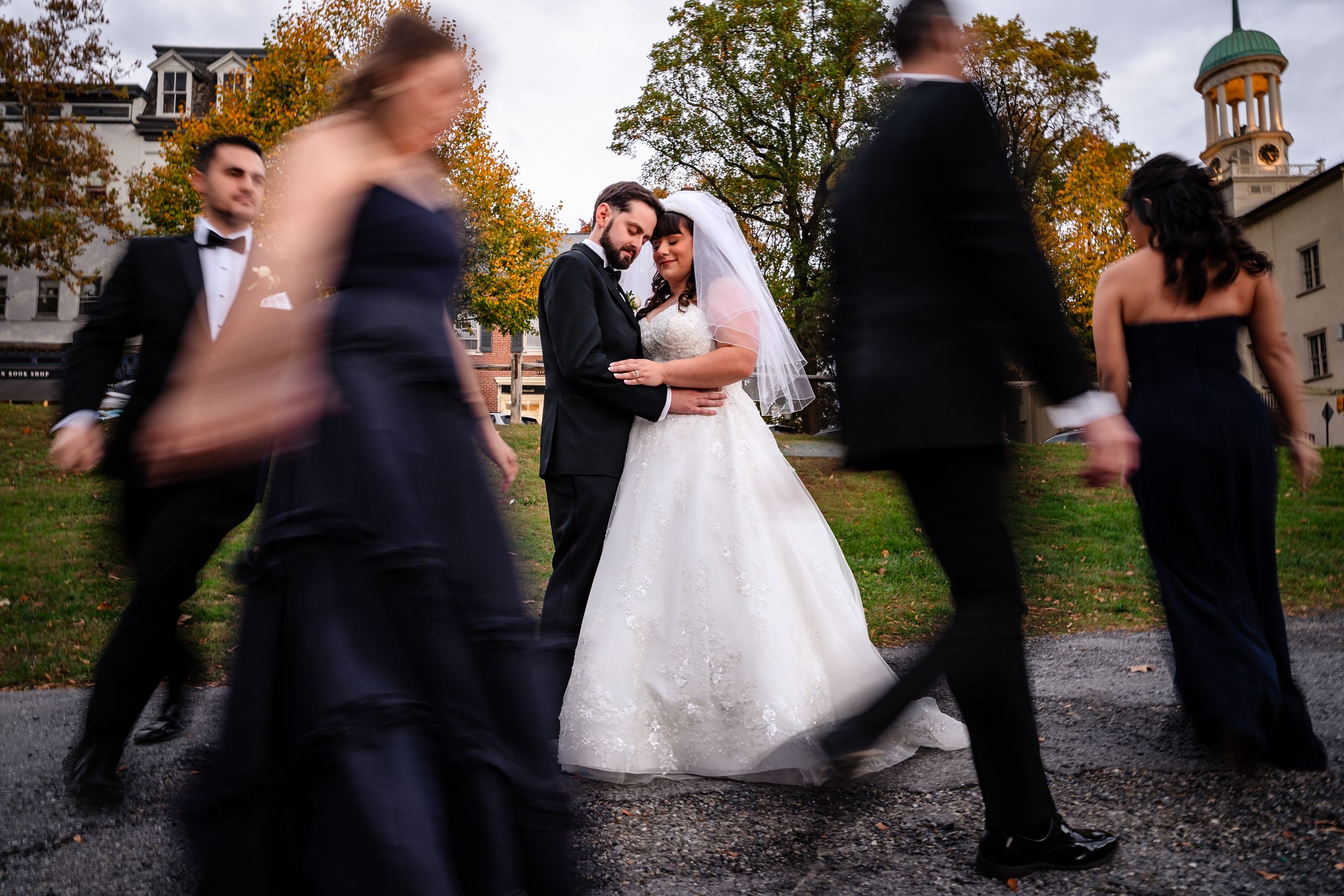 Wedding party members walking in line outside venue during fall season.