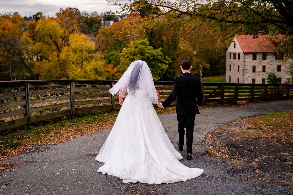 Autumn wedding photos on path surrounded by golden fall foliage.