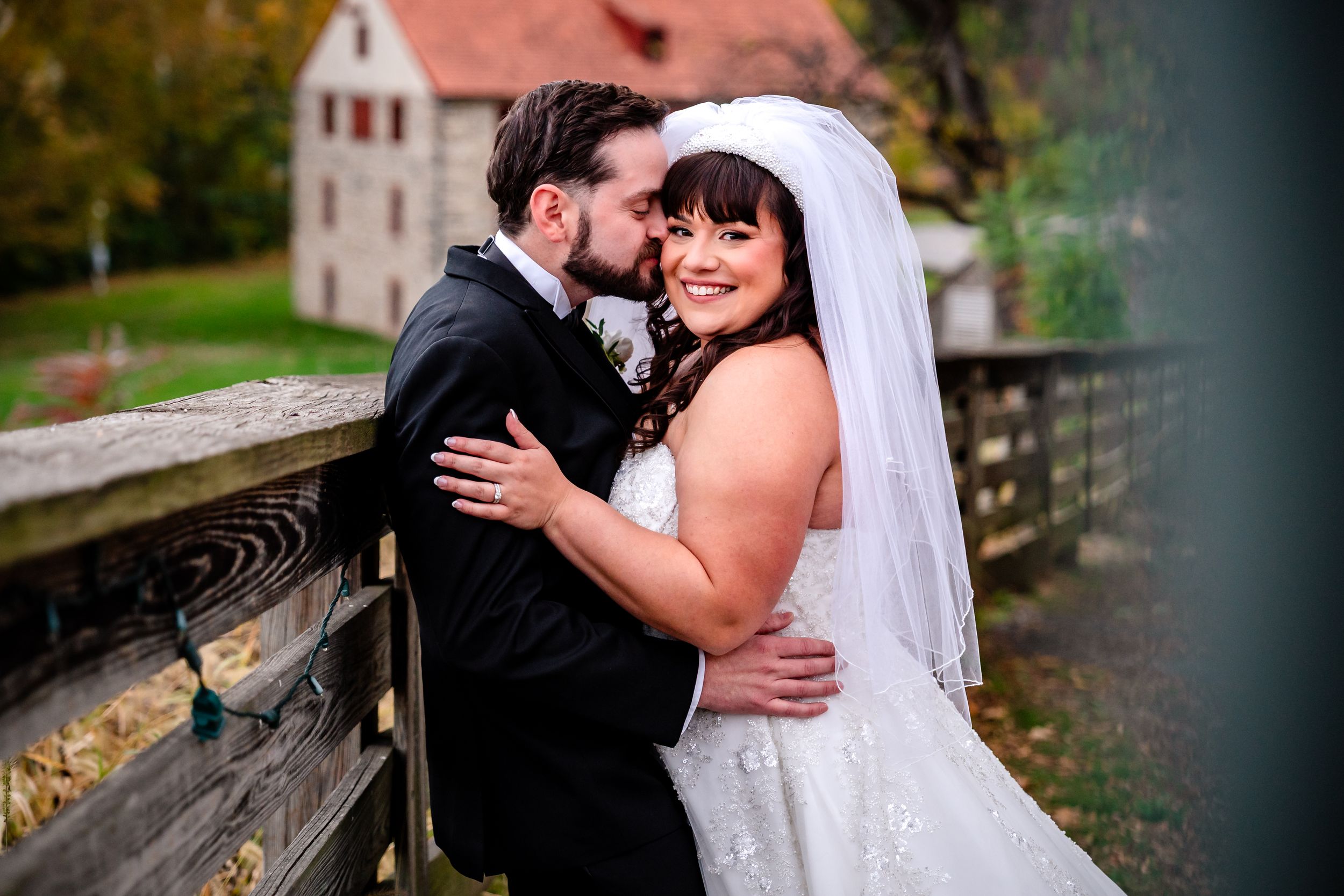 Romantic autumn wedding portraits against rustic building backdrop.