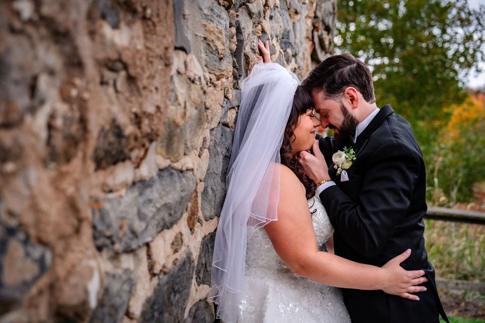 A romantic wedding moment captured against a rustic stone wall backdrop.