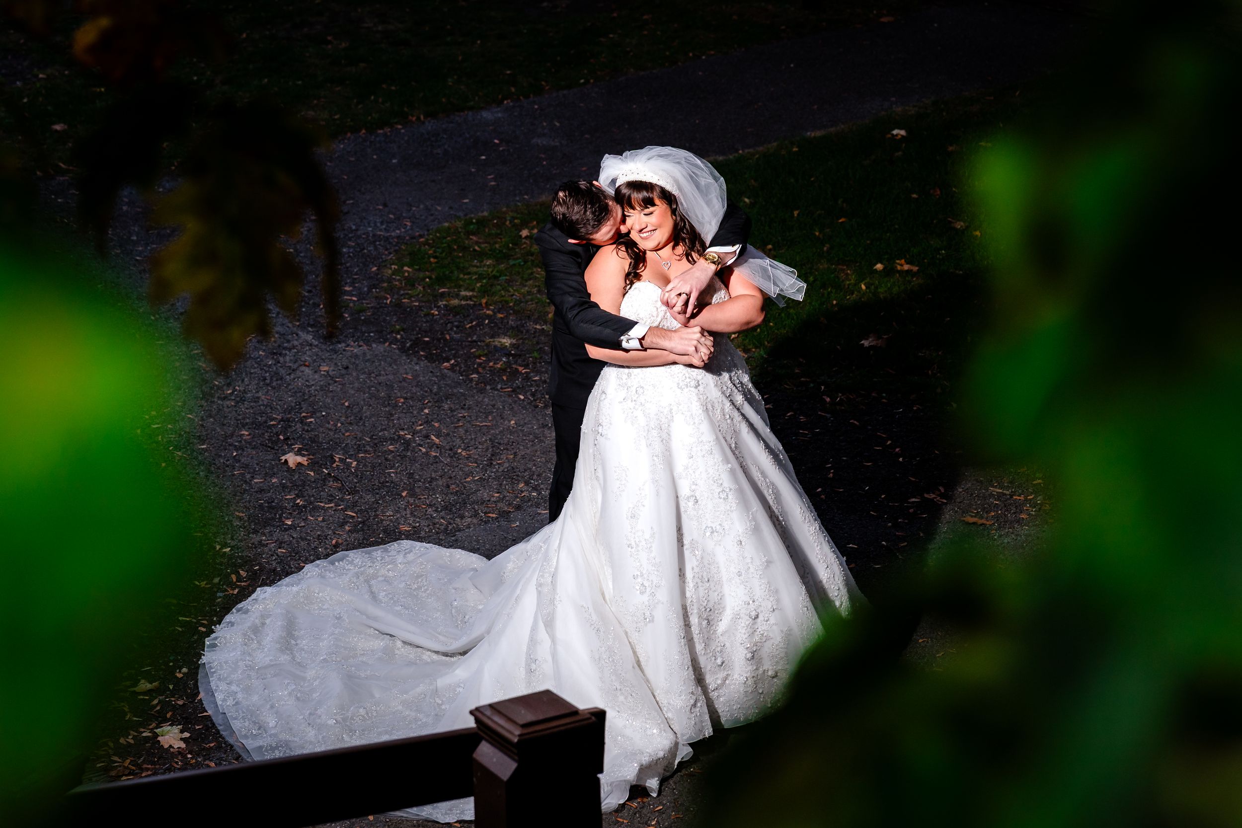 A romantic couple in wedding attire share an intimate dance outdoors at night, illuminated by dramatic lighting.