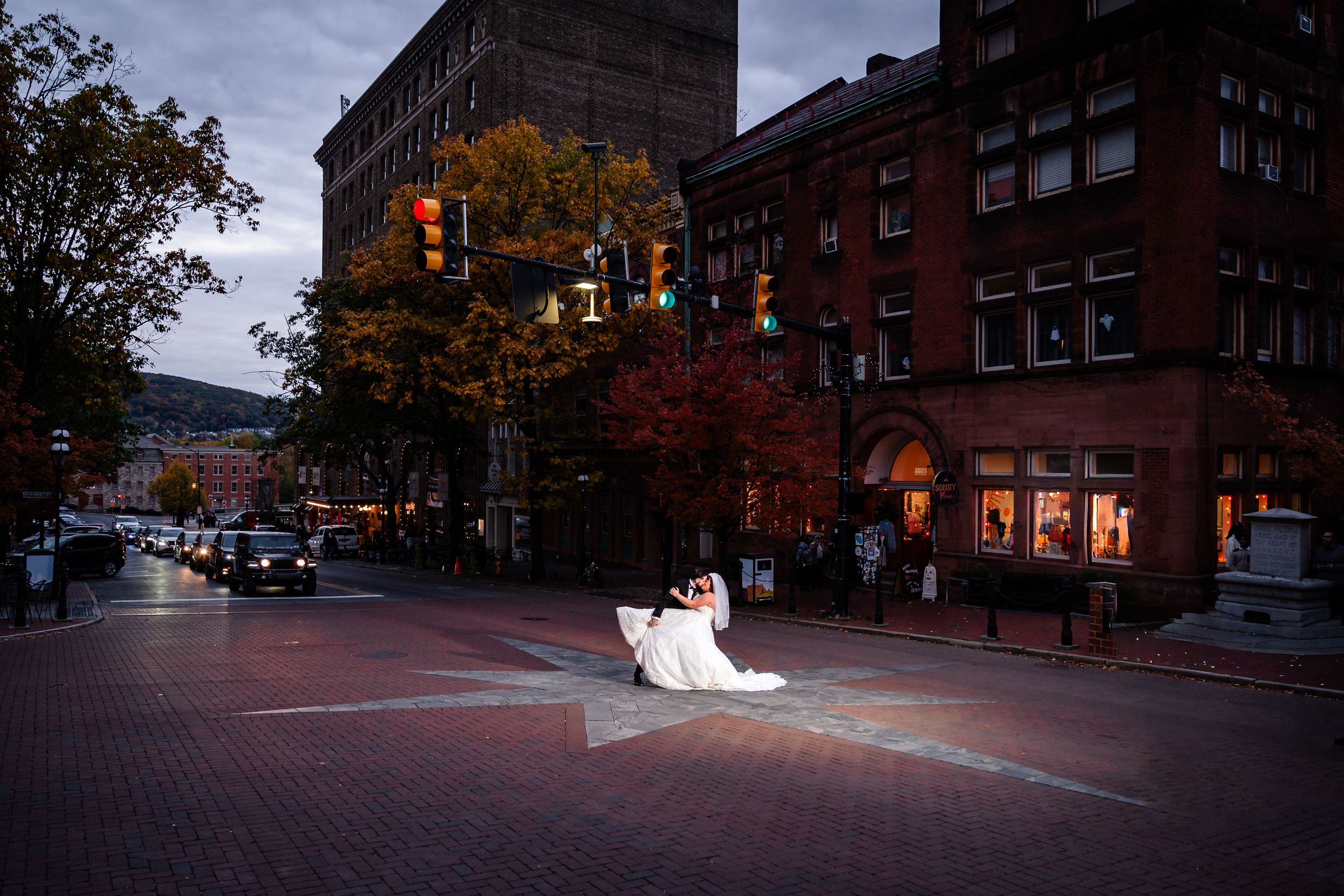 Autumn wedding photos captured on brick-lined streets with fall foliage and historic buildings at sunset.