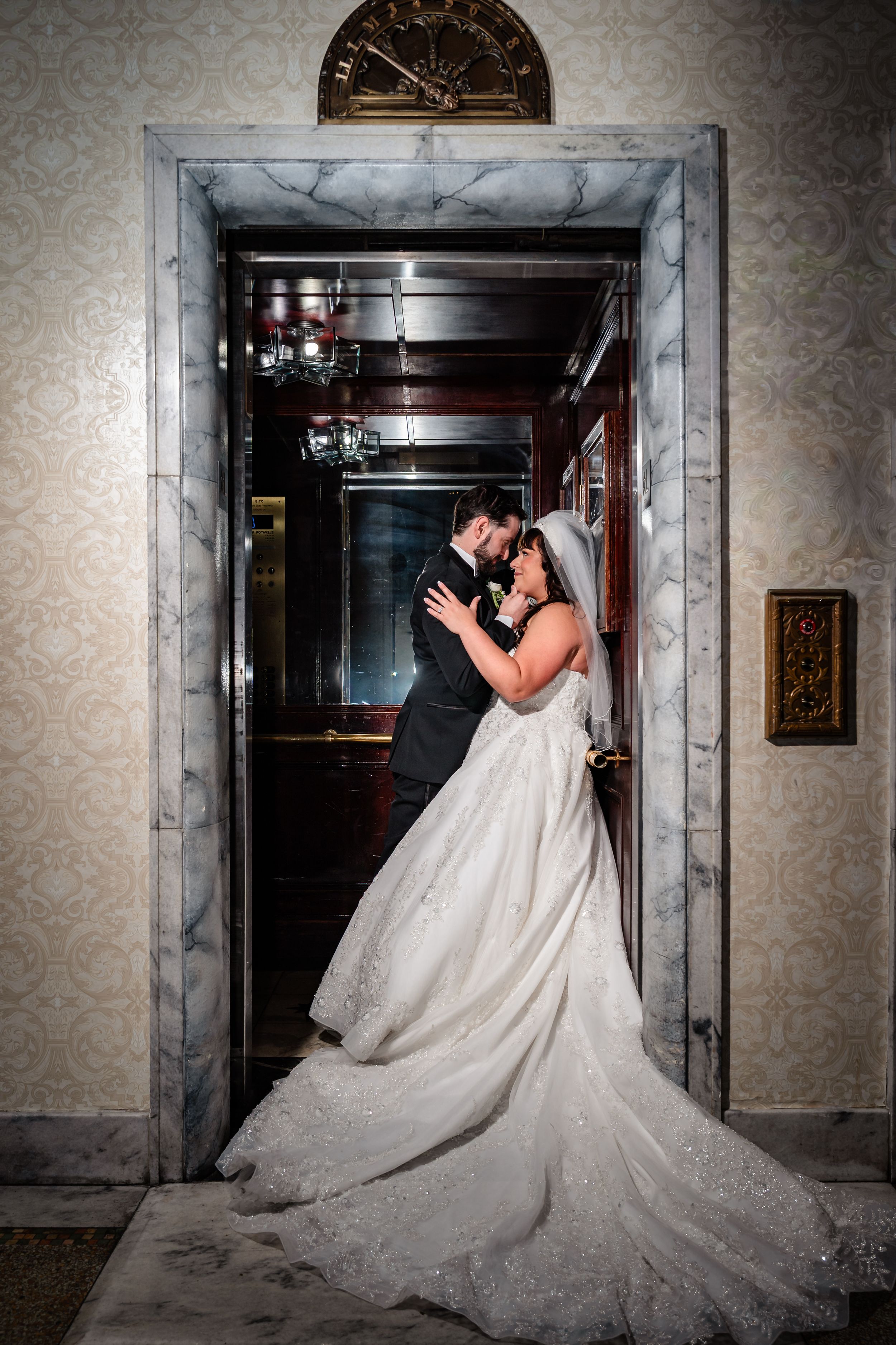 Dramatic wedding photos showing couple in elegant poses against textured wallpaper in dim hallway.