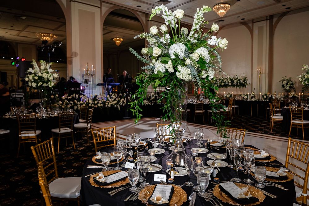 Elegant wedding reception tables decorated with white floral centerpieces and crystal chandeliers in a grand ballroom.