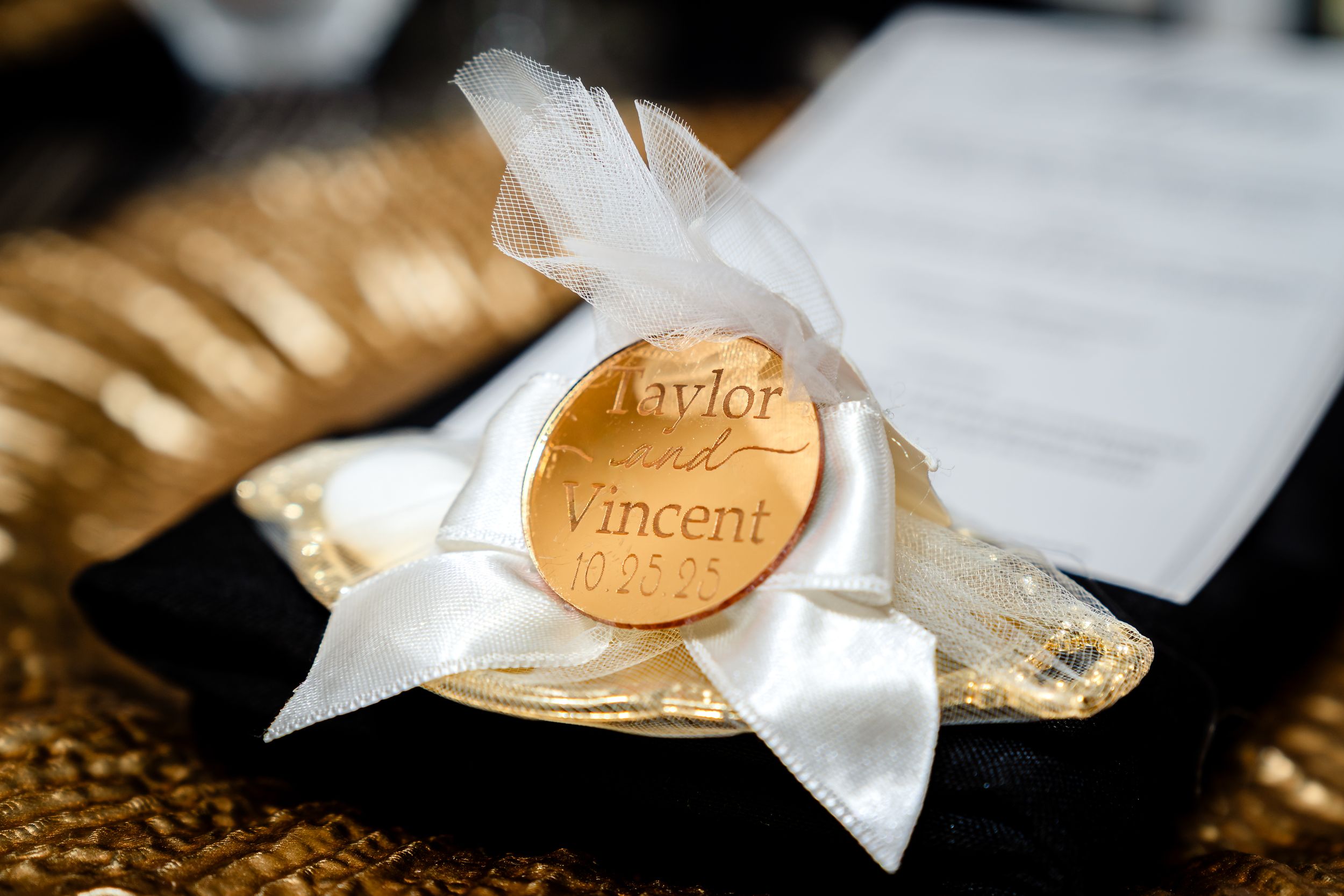 Close-up details of wrapped wedding favors with golden ribbons on dark background.