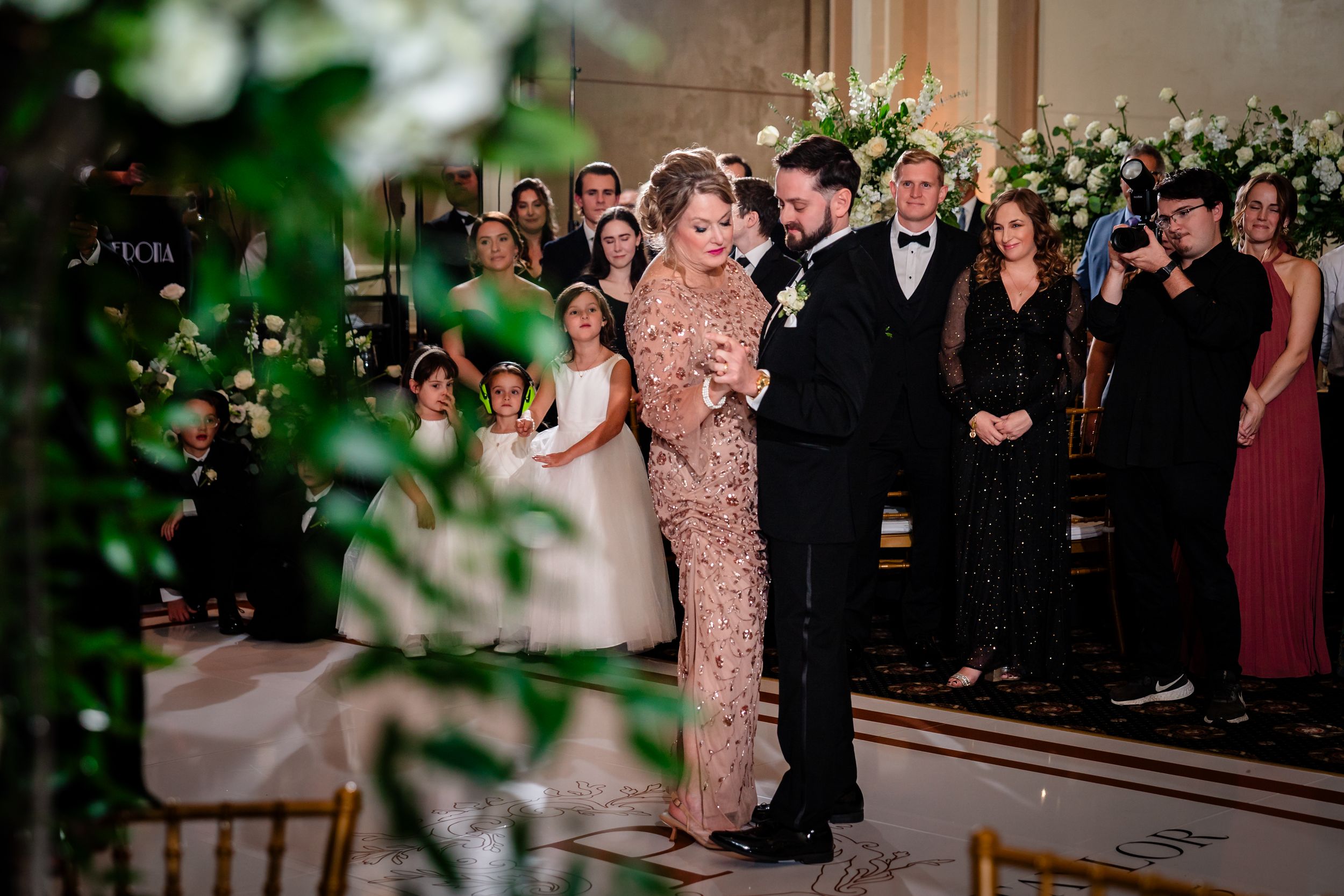 Wedding celebration in a grand ballroom with floral arrangements and formal decor.