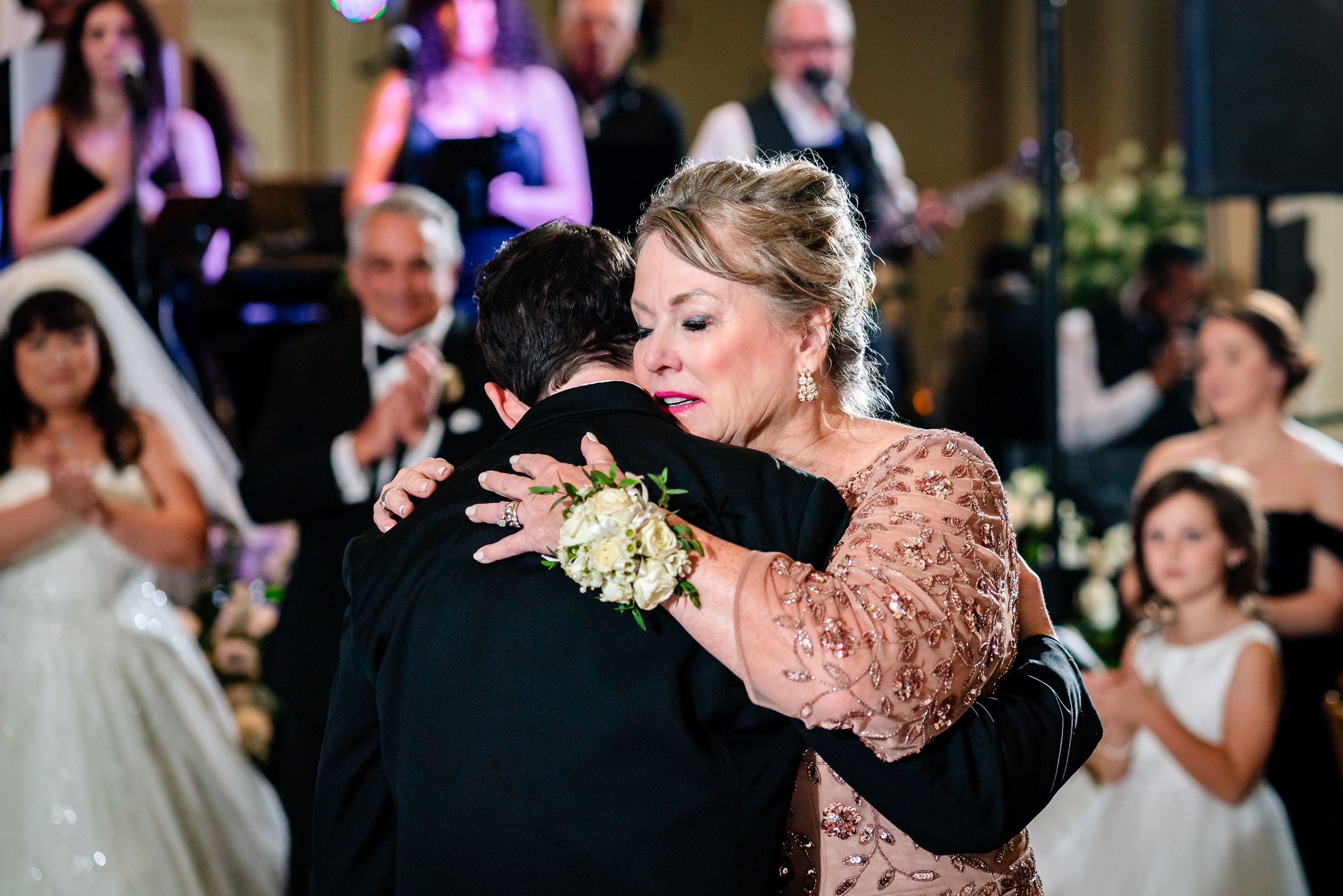 A tender dance moment at an elegant wedding reception with guests watching in the background.