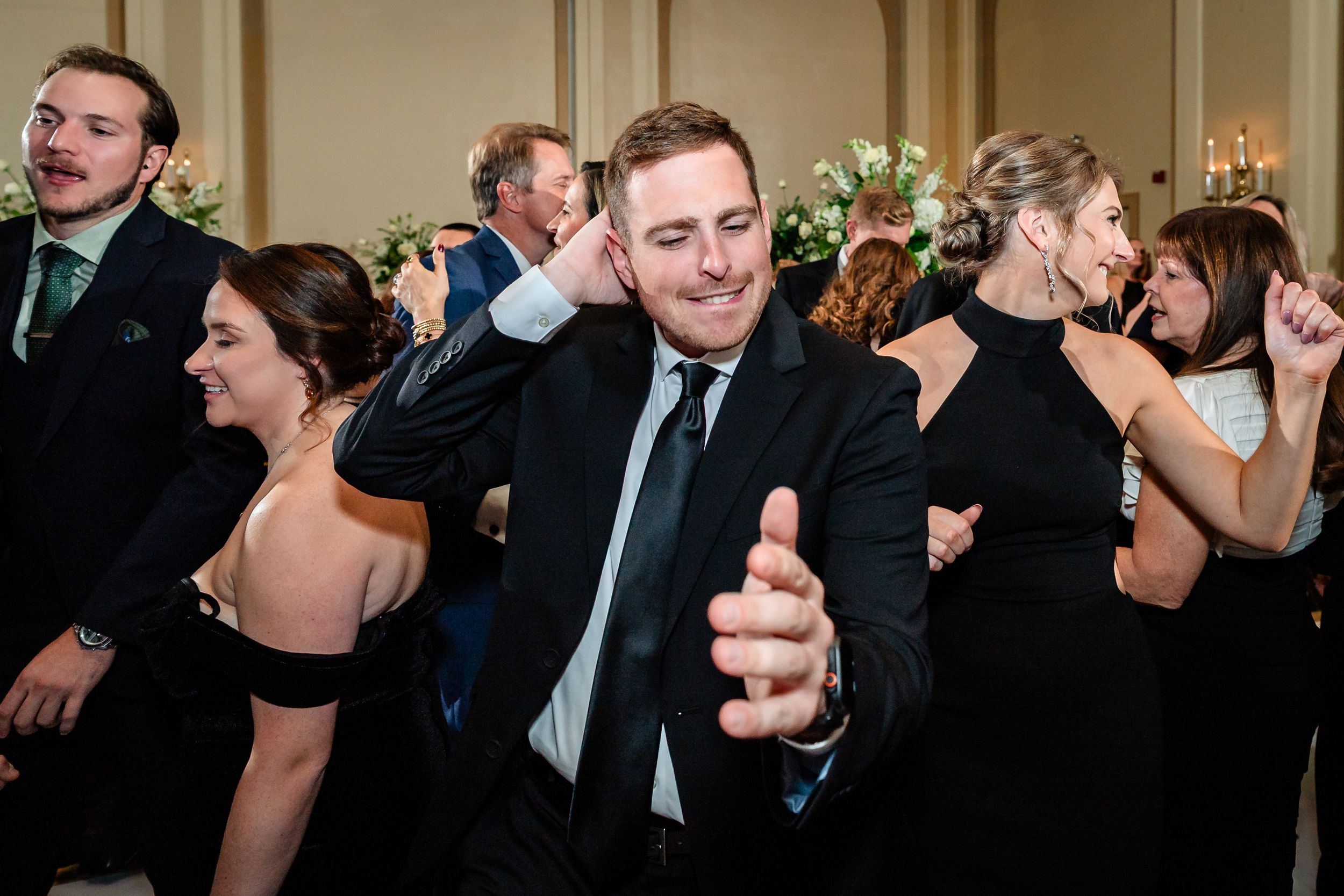 Wedding guests dancing and celebrating enthusiastically at a lively reception.