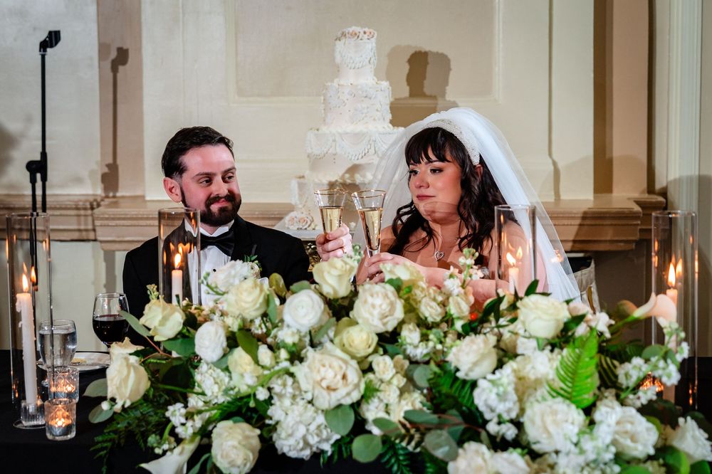Elegant wedding reception table decorated with white floral centerpieces and glowing candles in a formal dining setting.