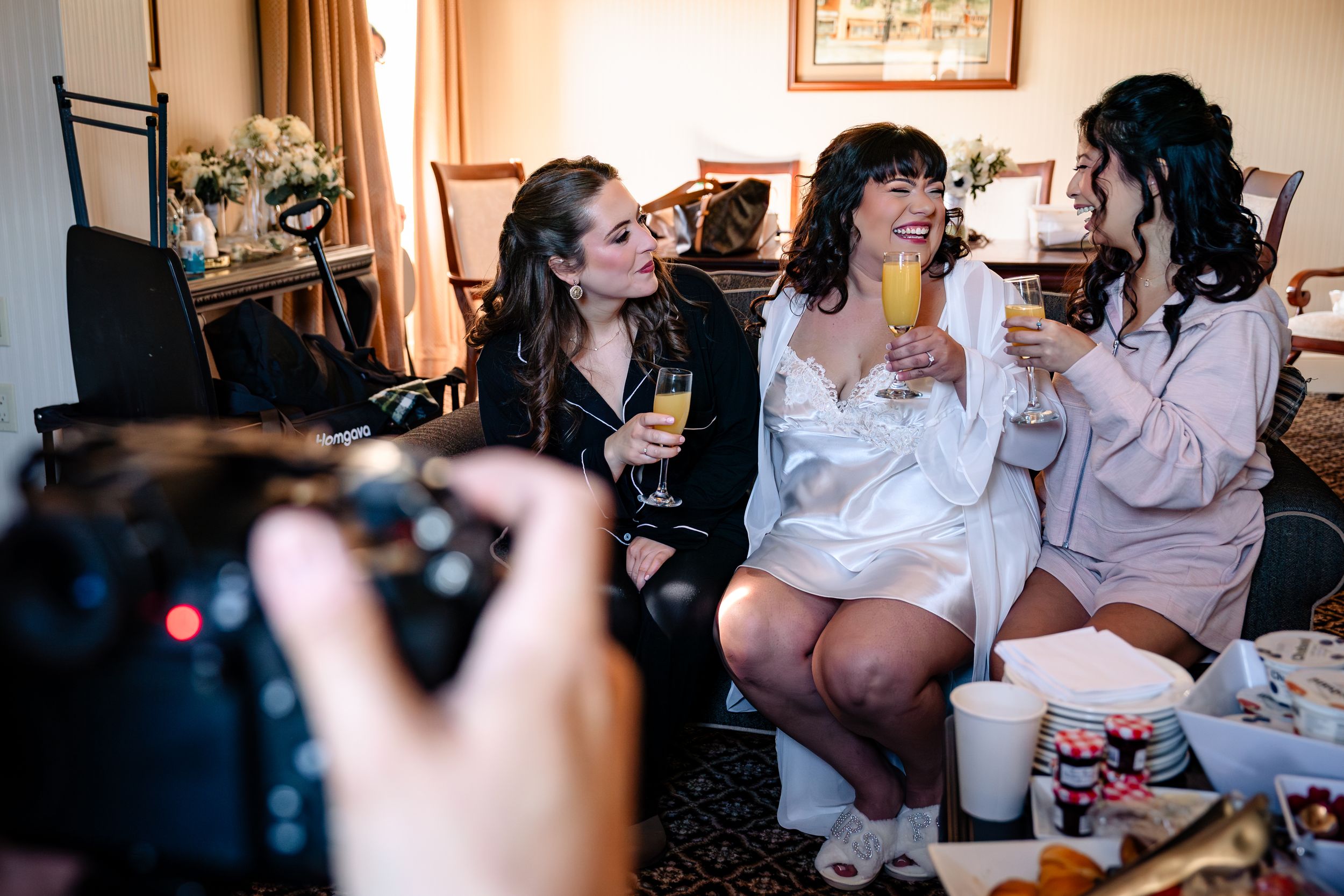 Wedding guests gather around tables in a warmly lit reception venue.
