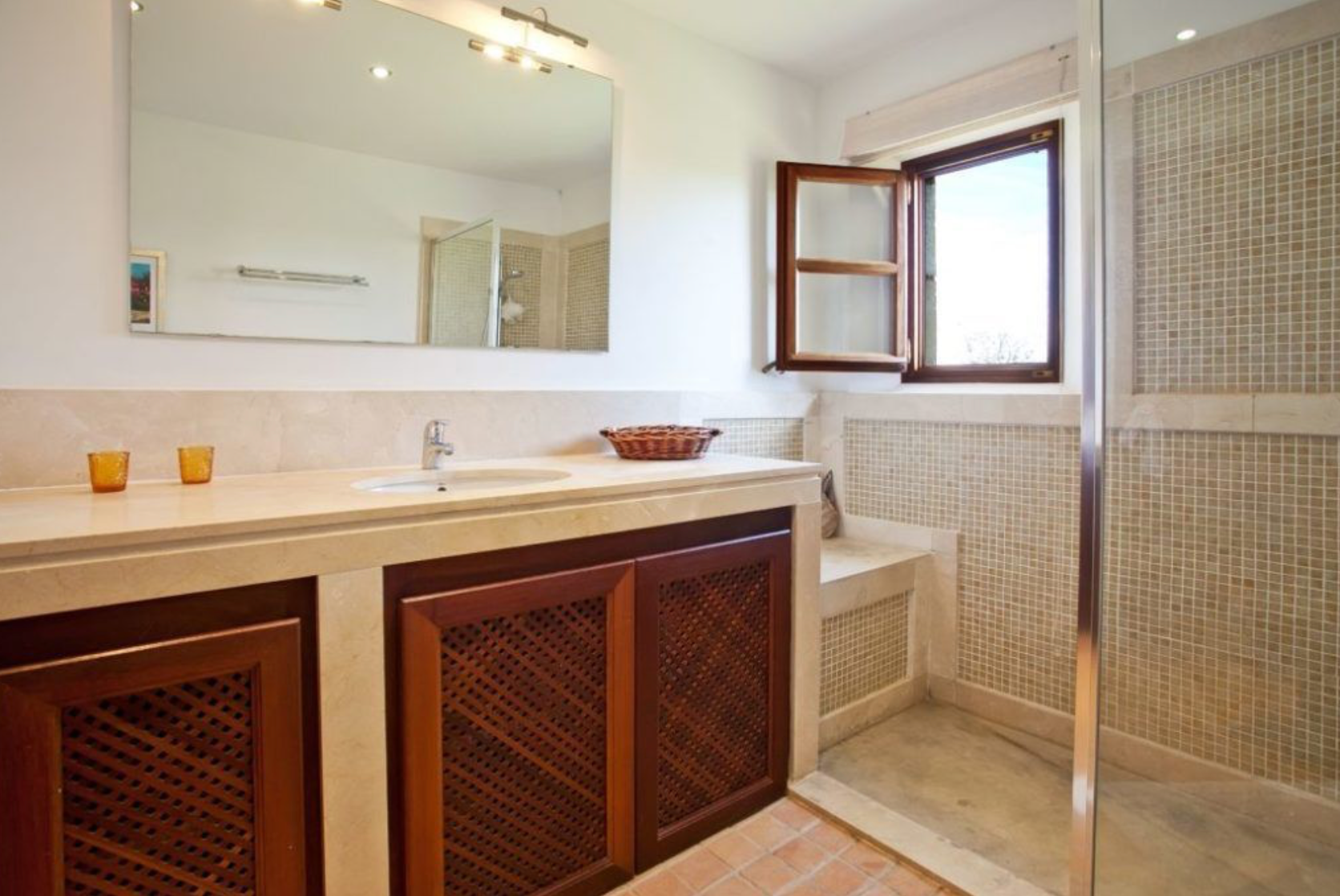 Modern bathroom interior with dark wood vanity, white countertop, and glass shower partition in neutral tones.