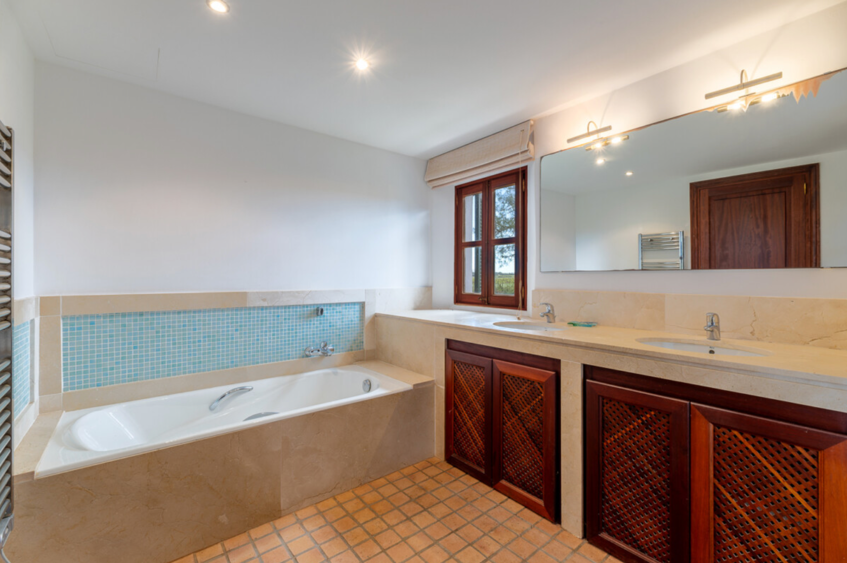 Modern white bathroom interior with sloped ceiling, recessed lighting, and wooden accents.
