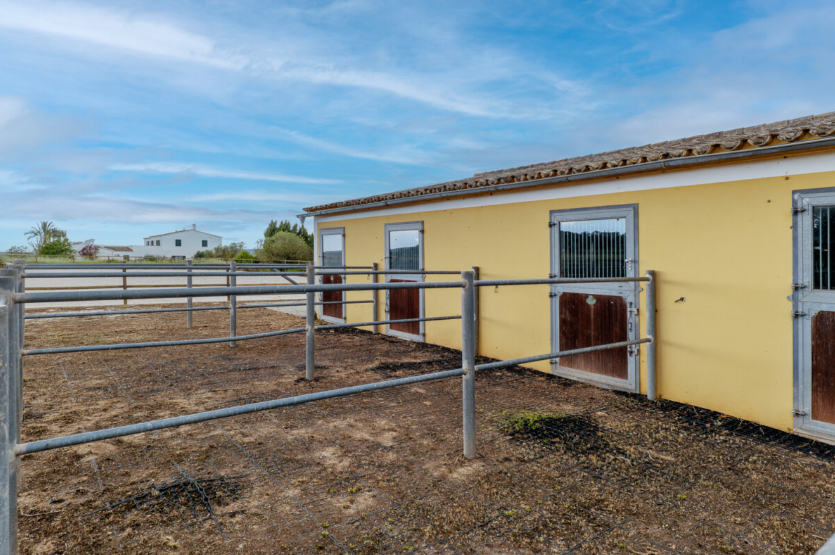A series of modular buildings are positioned on a hillside under a bright blue sky with wispy clouds.