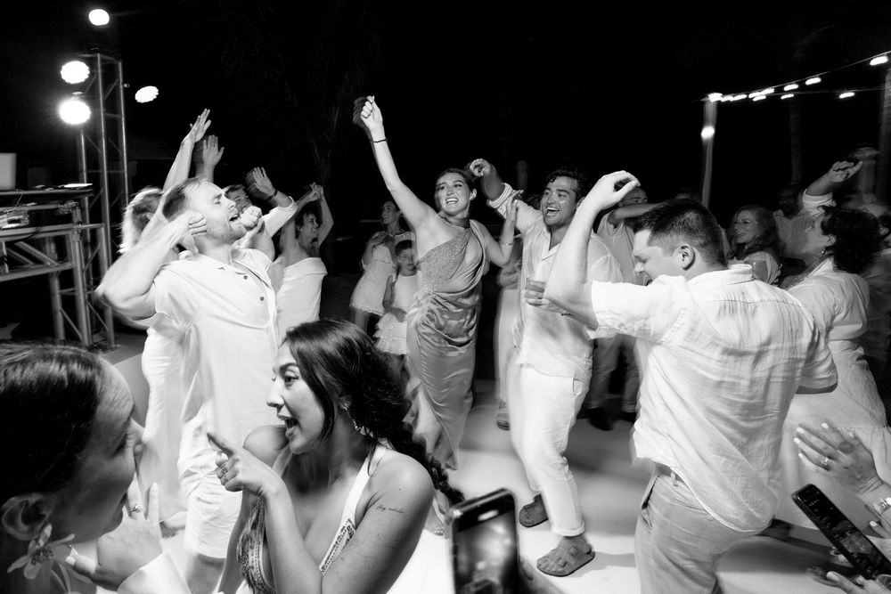 A group of people dancing and celebrating at a lively party with their hands raised in the air.