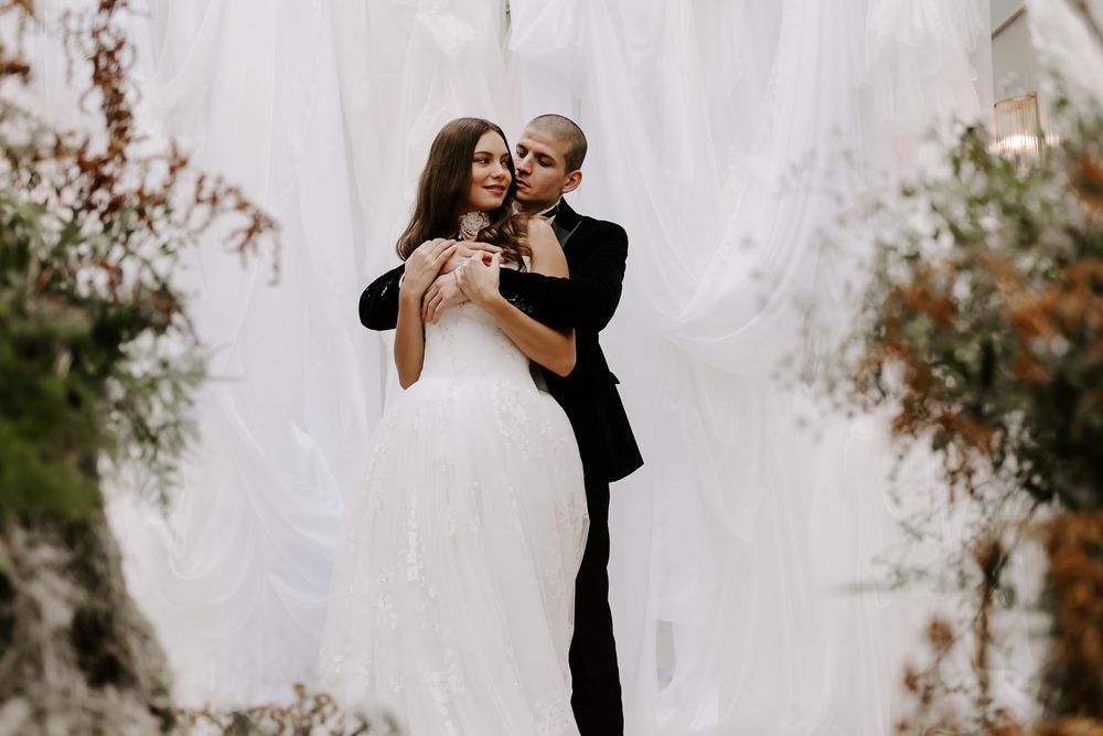 Romantic outdoor photo session with autumn foliage and white fabric backdrop creating a dreamy atmosphere.