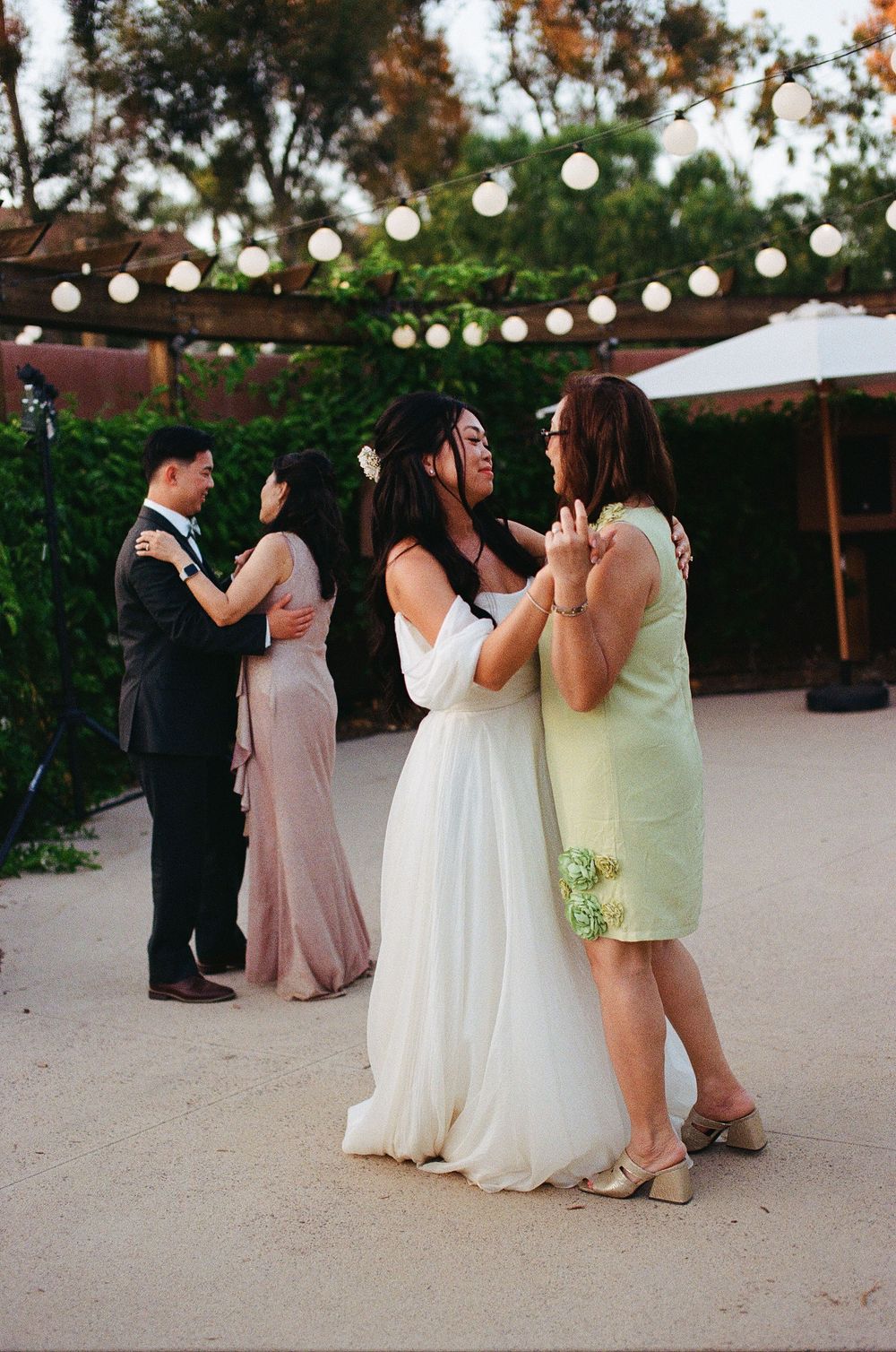 Emotional film photography of the couple dancing with their mothers and fathers during the Gold Coast Farms wedding reception.