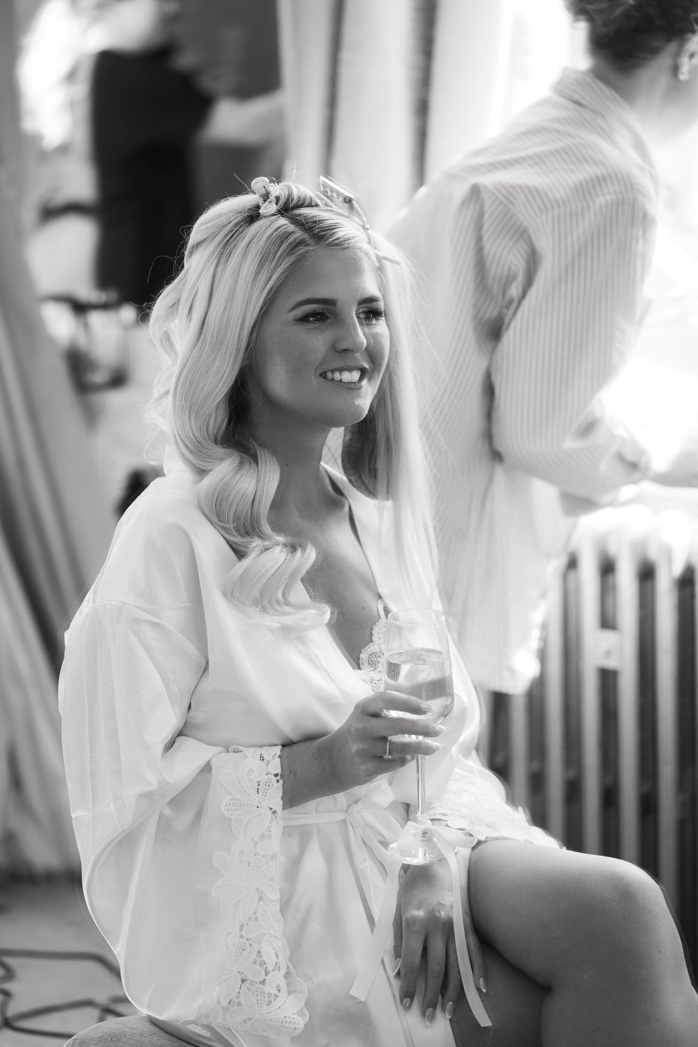 Black and white photo series showing bride getting ready in white robe while laughing and smiling during wedding preparations.
