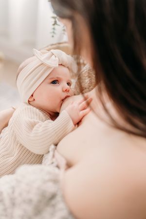 Portrait d’une mère allaitant son bébé qui la regarde amoureusement une main posée sur son sein