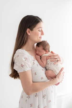 Photographie d'une maman et de son nouveau-né au studio de Québec dans une robe blanche et fleurie de la garde-robe cliente du studio