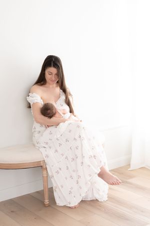 Photographie d'une maman allaitant son nouveau-né au studio de Québec dans une robe blanche et fleurie de la garde-robe cliente du studio