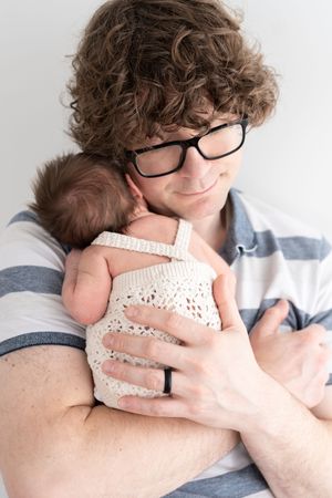 Photographie d'un papa tenant son son nouveau-né tendrement contre lui au studio de Québec
