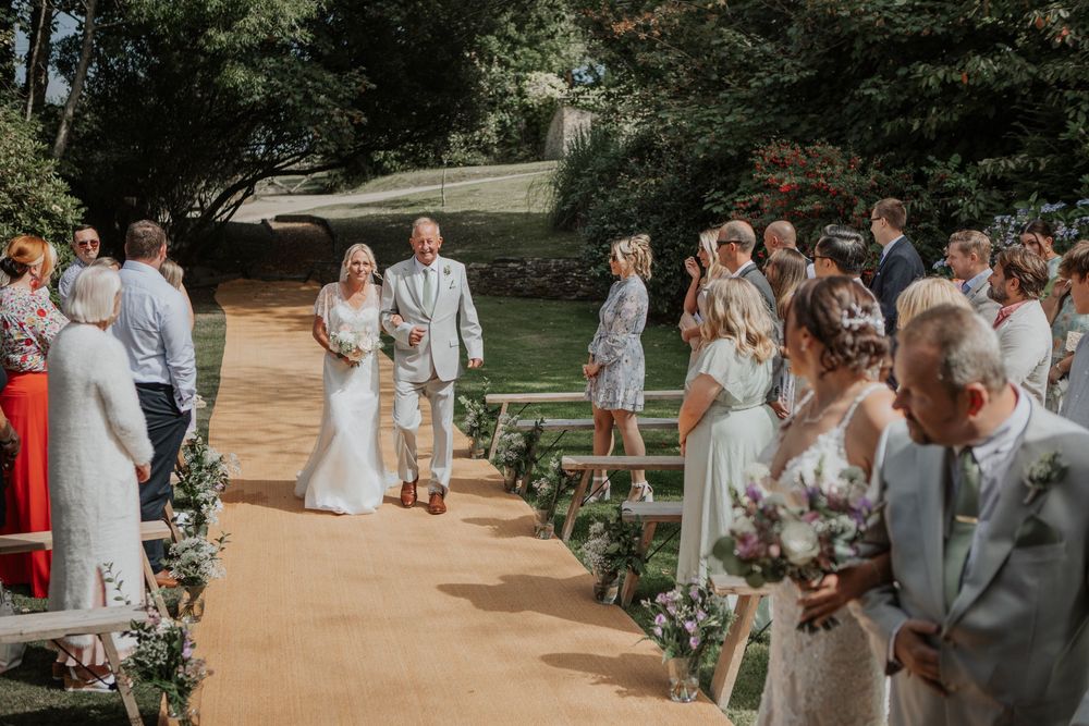 Newlywed couple walking back down the aisle past cheering guests at an outdoor garden wedding ceremony.