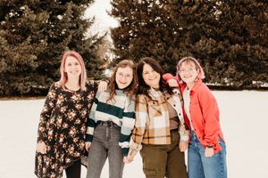A group of friends laugh and smile together during a winter photo session in the snow.