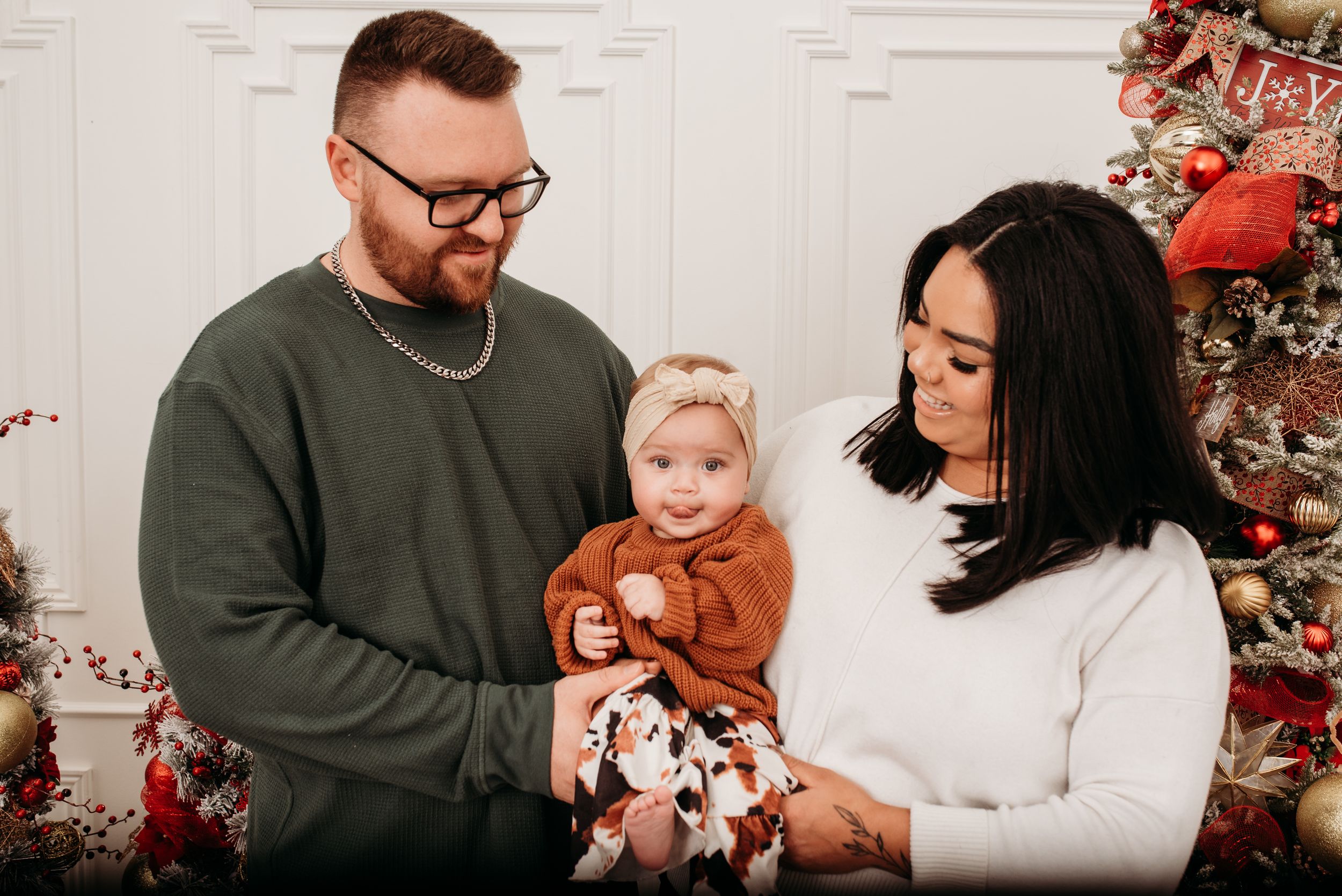 A family sits together in front of a decorated Christmas tree during a holiday photo session.