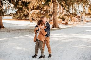 Two children embrace in a warm hug while standing on a path under trees with Spanish moss.