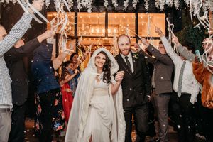 Wedding guests toss autumn leaves in celebration as a couple walks through during an outdoor fall ceremony.
