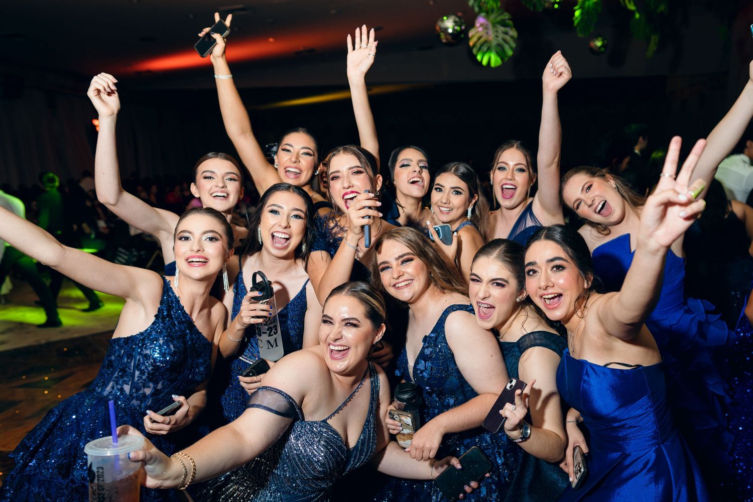 Celebratory group photo with people in formal attire raising hands in excitement.