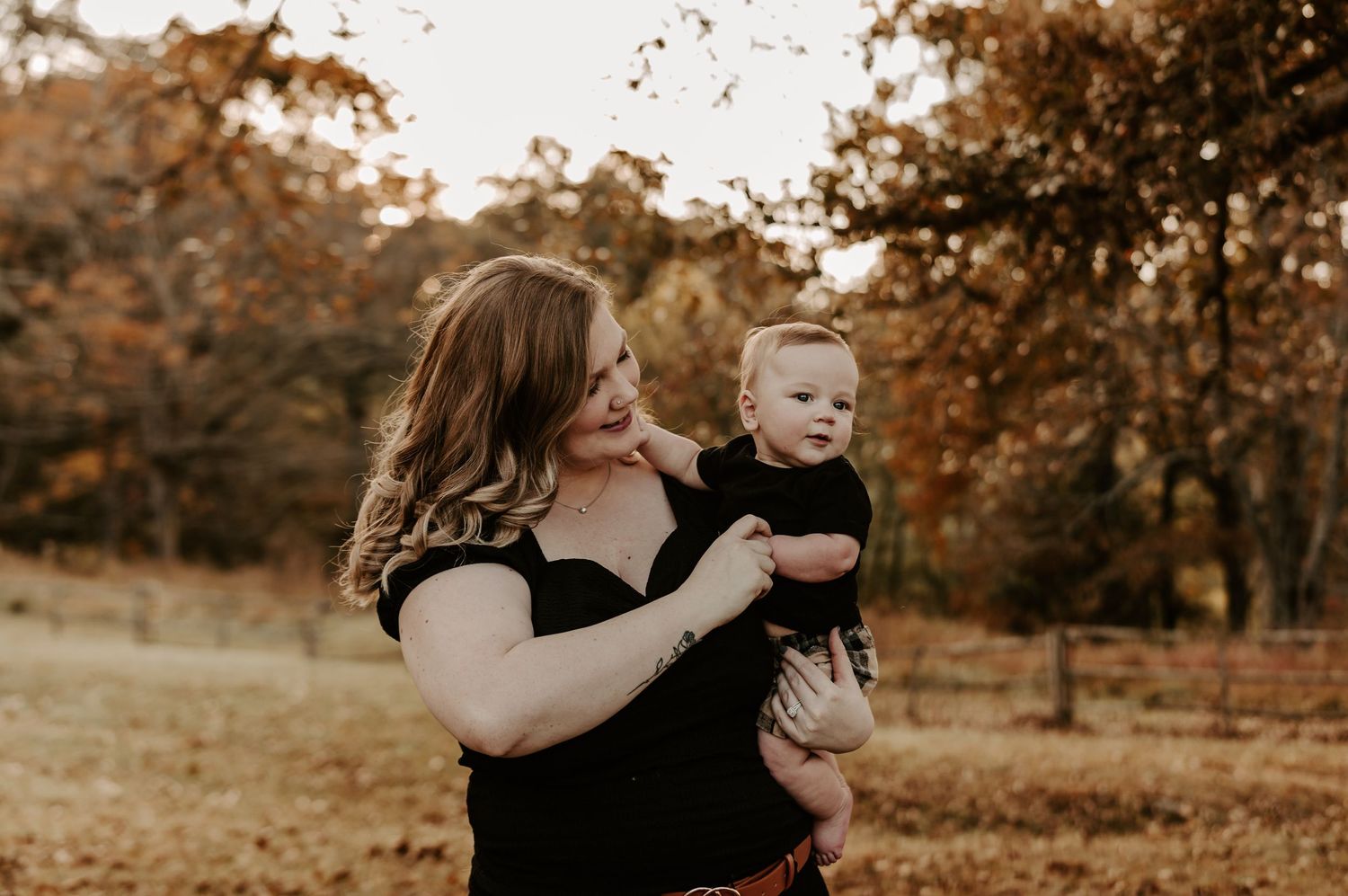 Autumn outdoor family photoshoot with warm golden light filtering through fall foliage.