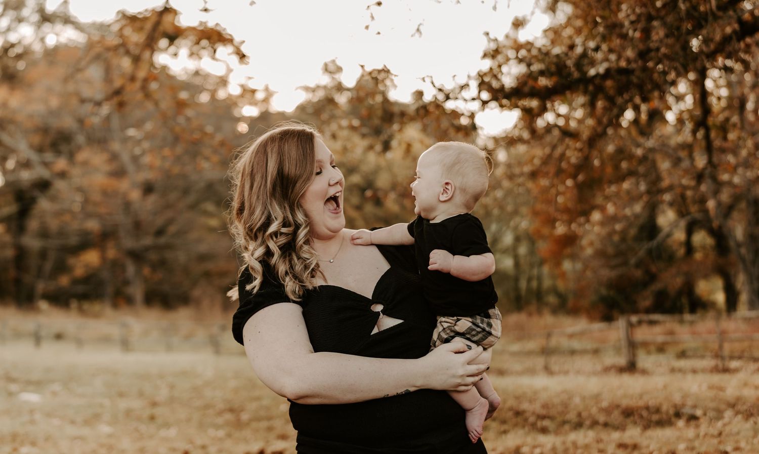 Family portrait session in a golden autumn field with warm sunset lighting.