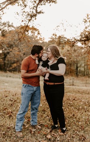 Family enjoying playful moments together during an autumn outdoor photo session.