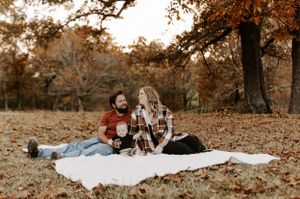 Panoramic view of a family relaxing on a blanket in a fall landscape setting.