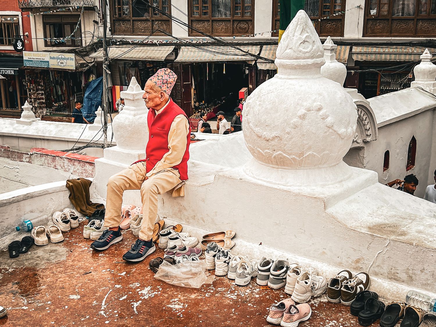 Nepali man in traditional hat looks after visitors shoes outside the Buddha Stupa in Kathmandu, Nepal