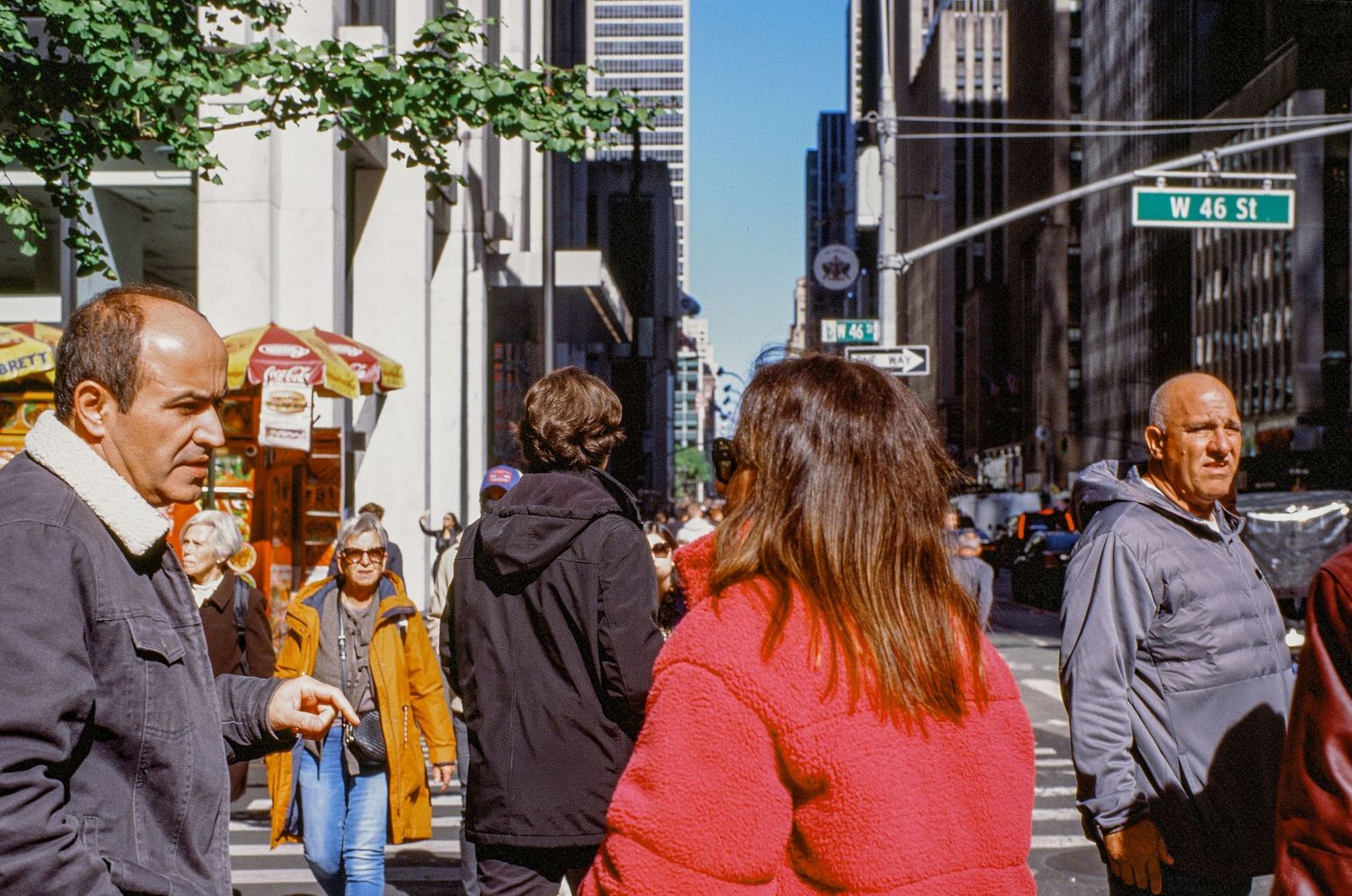 Busy street corner in New York City with people waiting to cross.