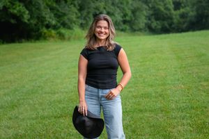 Casual outdoor photoshoot featuring a woman in denim and black top against lush greenery.