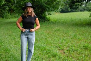 Someone poses in casual attire against a backdrop of green summer grass.