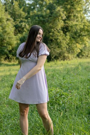 Woman in striped dress playing in green summer field.