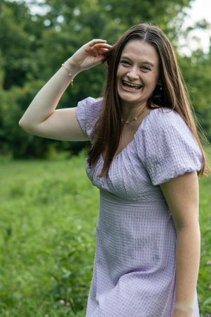 Someone in a white summer dress strikes cheerful poses outdoors among greenery.