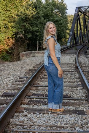 Person in overalls poses on railroad tracks at different angles.
