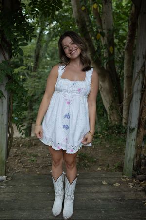 Summer fashion photography with white western boots and flowing dress in a natural setting.